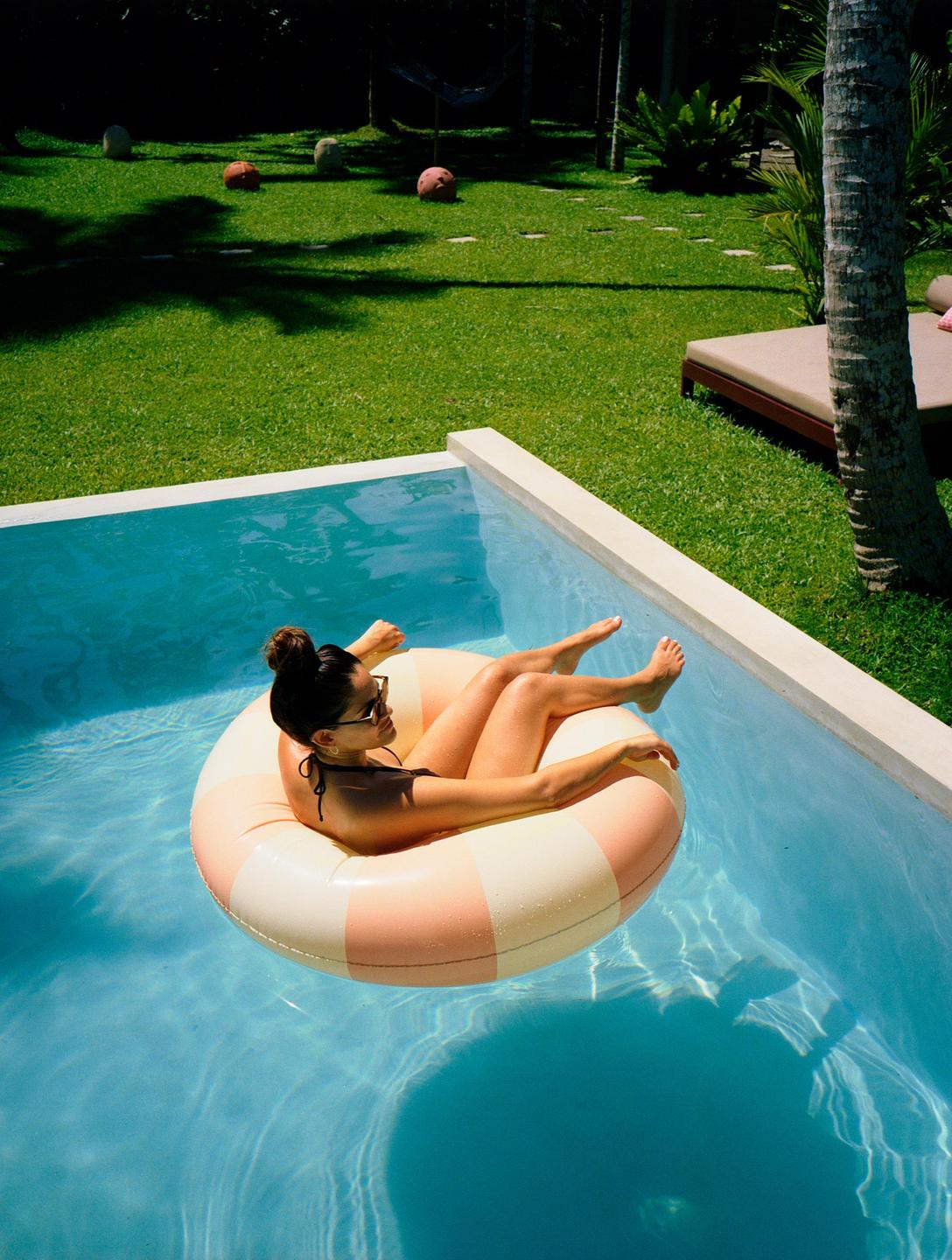 A woman floats in a swimming pool on an inflatable ring.