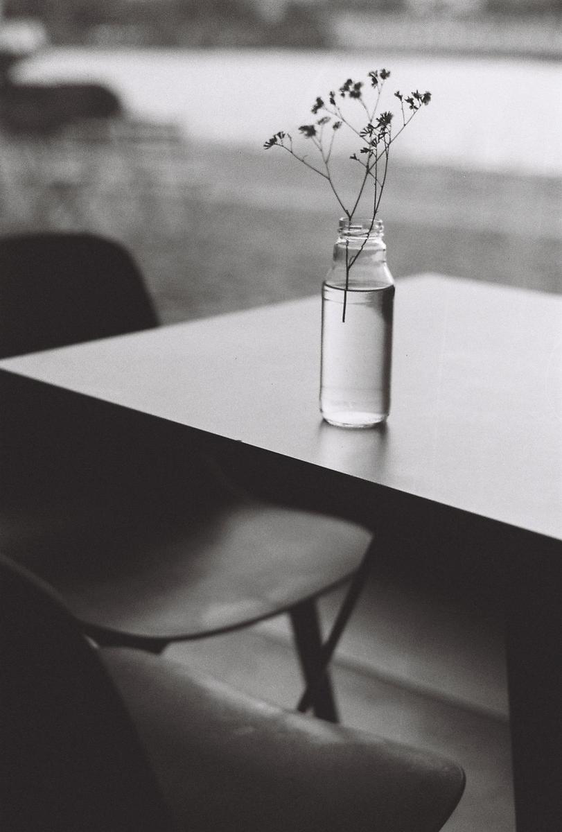 A small bottle with delicate flowers sits on a table next to a chair.