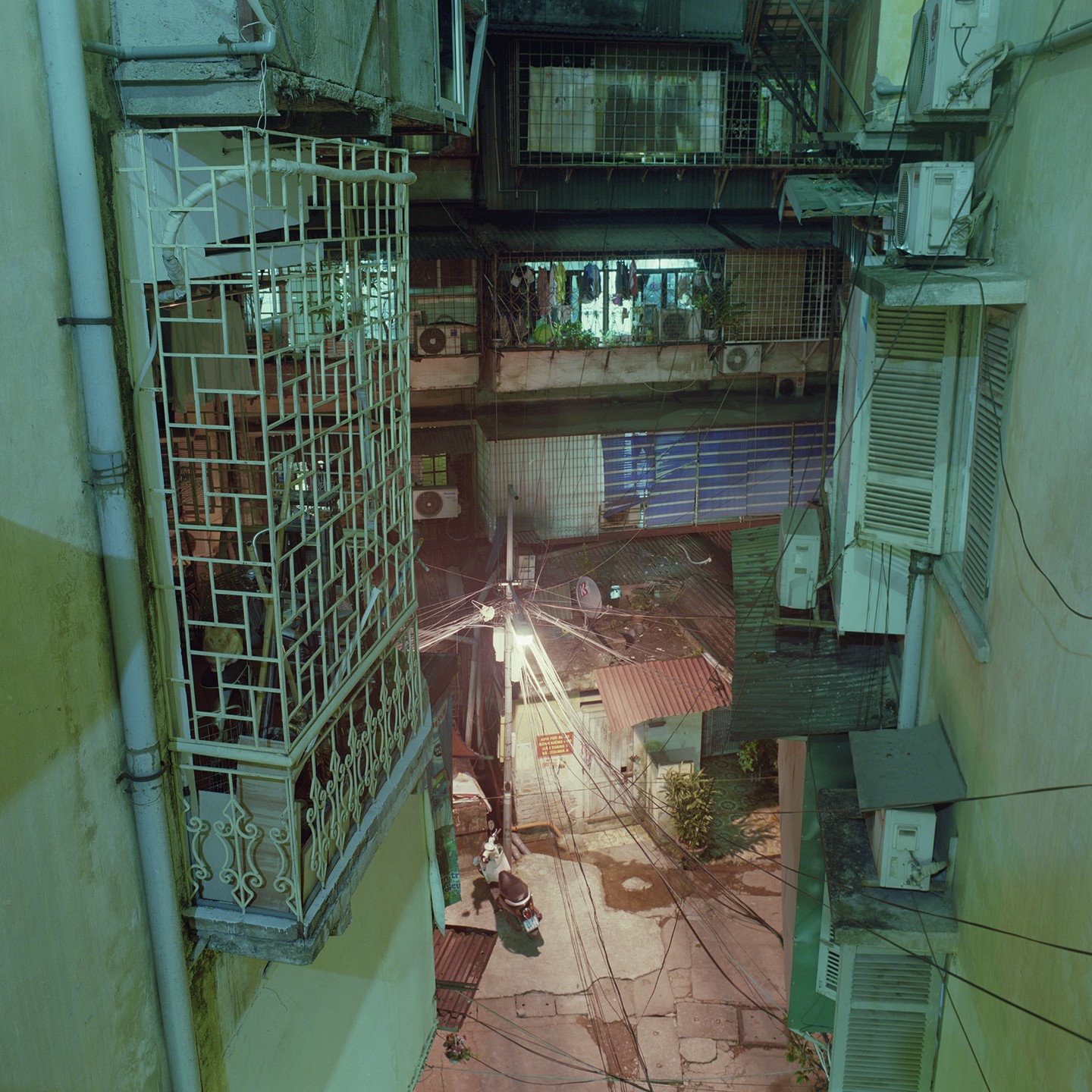 A narrow alleyway is visible from above, surrounded by buildings with balconies and air conditioning units.