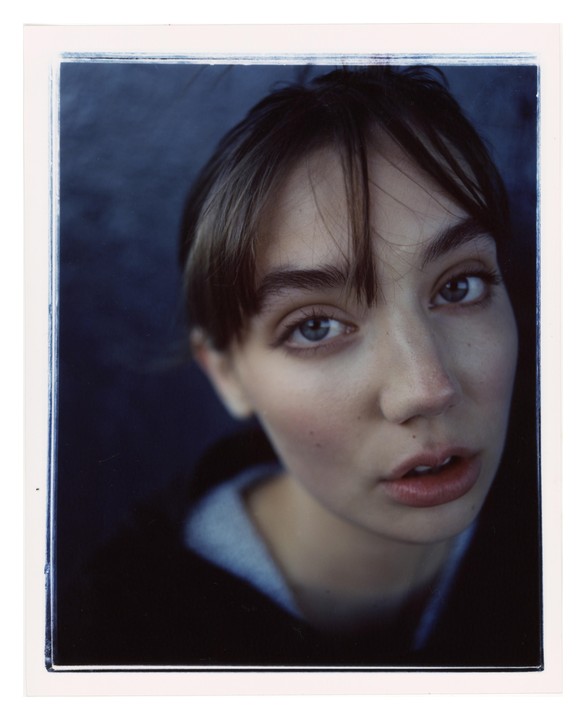 A woman with bangs looks directly at the viewer.