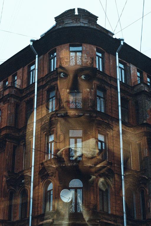 A double exposure shows a woman's face superimposed over a building with many windows and balconies.
