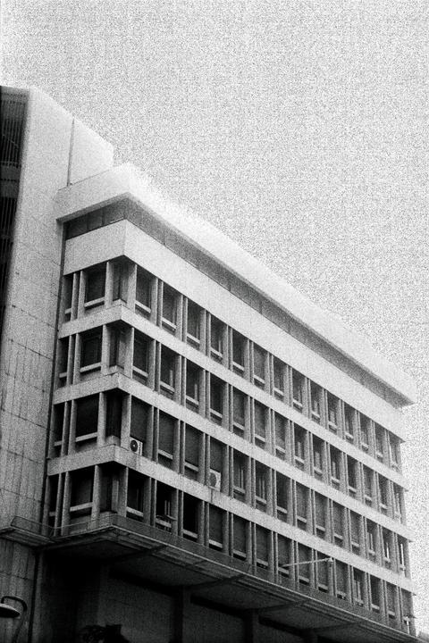 A tall building with many windows is shown from a low angle.