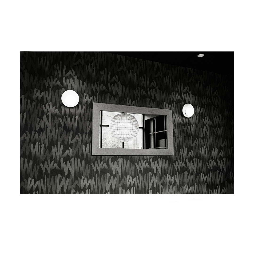 A disco ball is reflected in a mirror on a wall with a graffiti pattern.