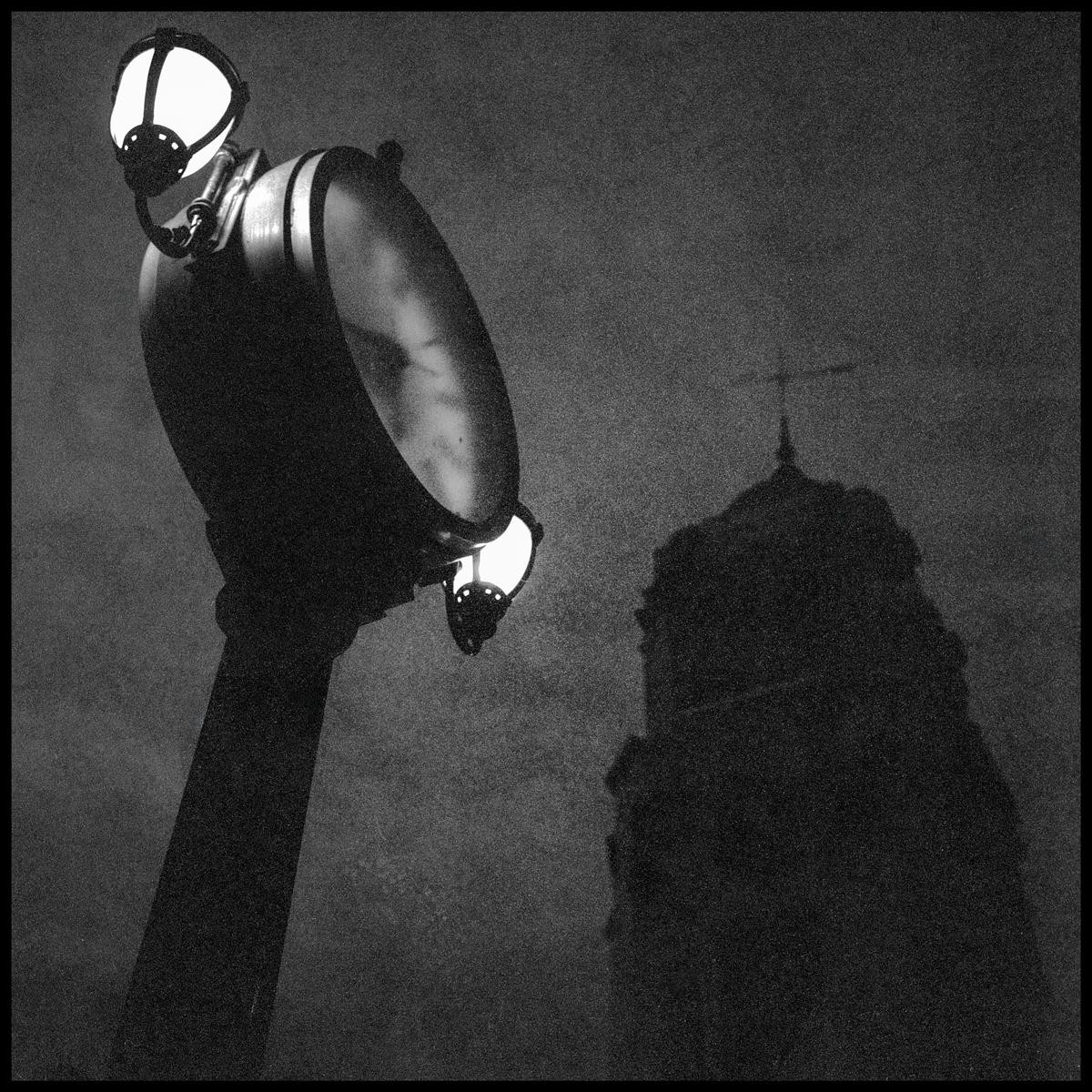 A street light illuminates a dark building with a cross on top.