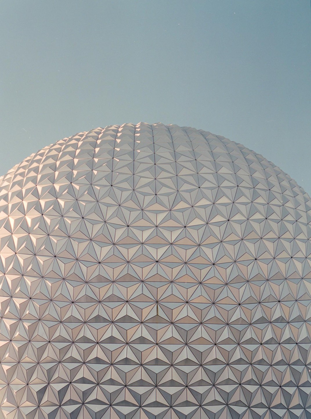 A geodesic dome with a geometric pattern covers the entire frame under a clear sky.