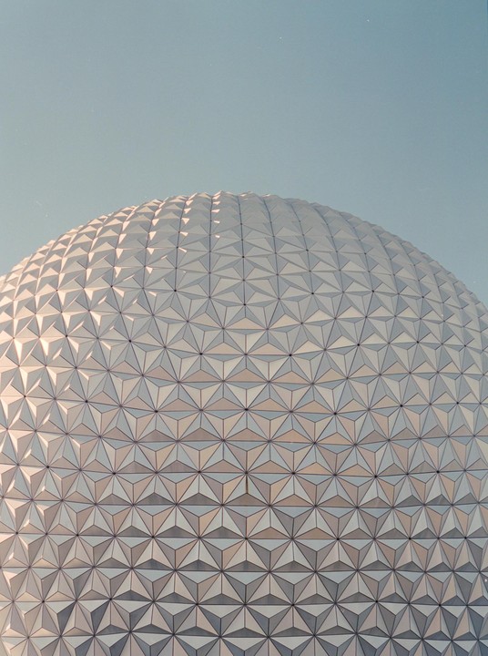 A geodesic dome with a geometric pattern covers the entire frame under a clear sky.