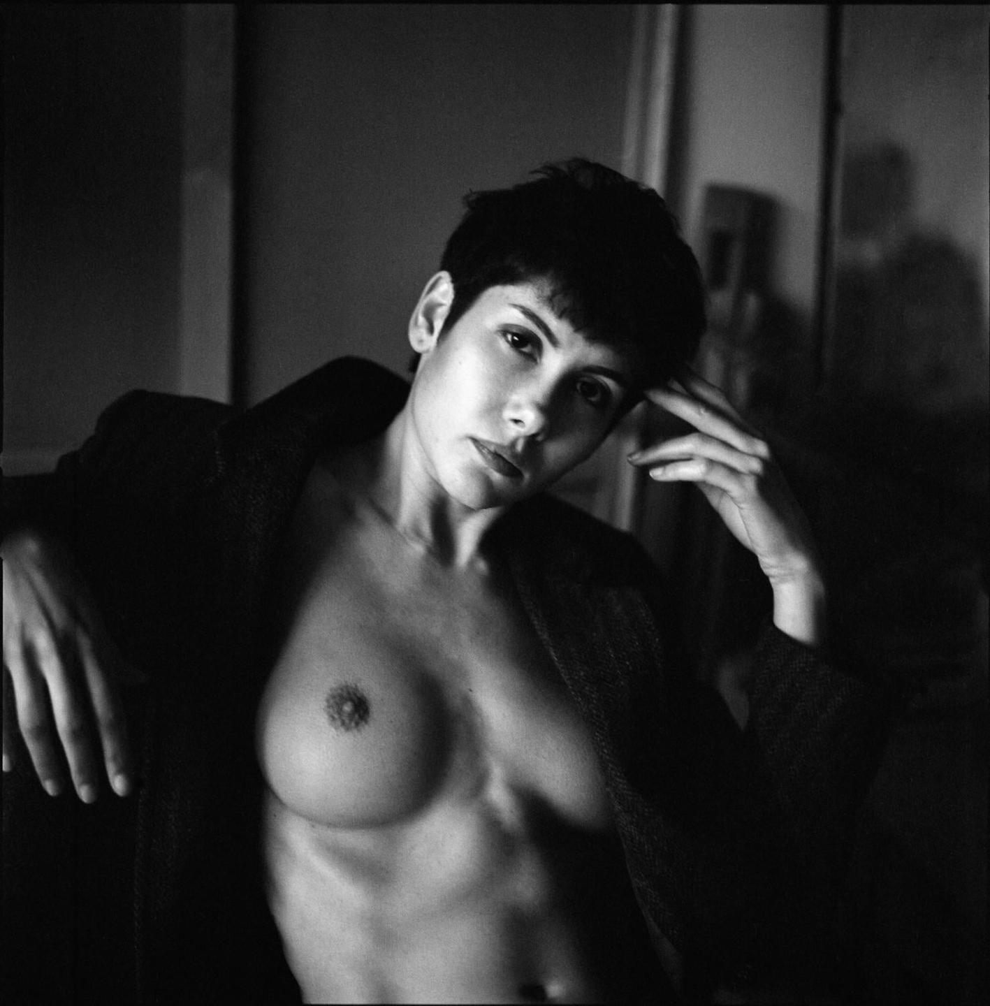 A woman with short hair and an open jacket poses for a portrait.