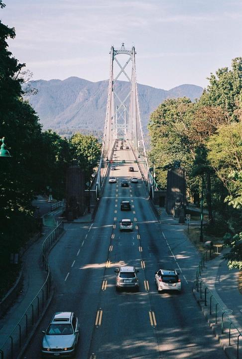 Cars drive on a bridge with a mountain range in the background.