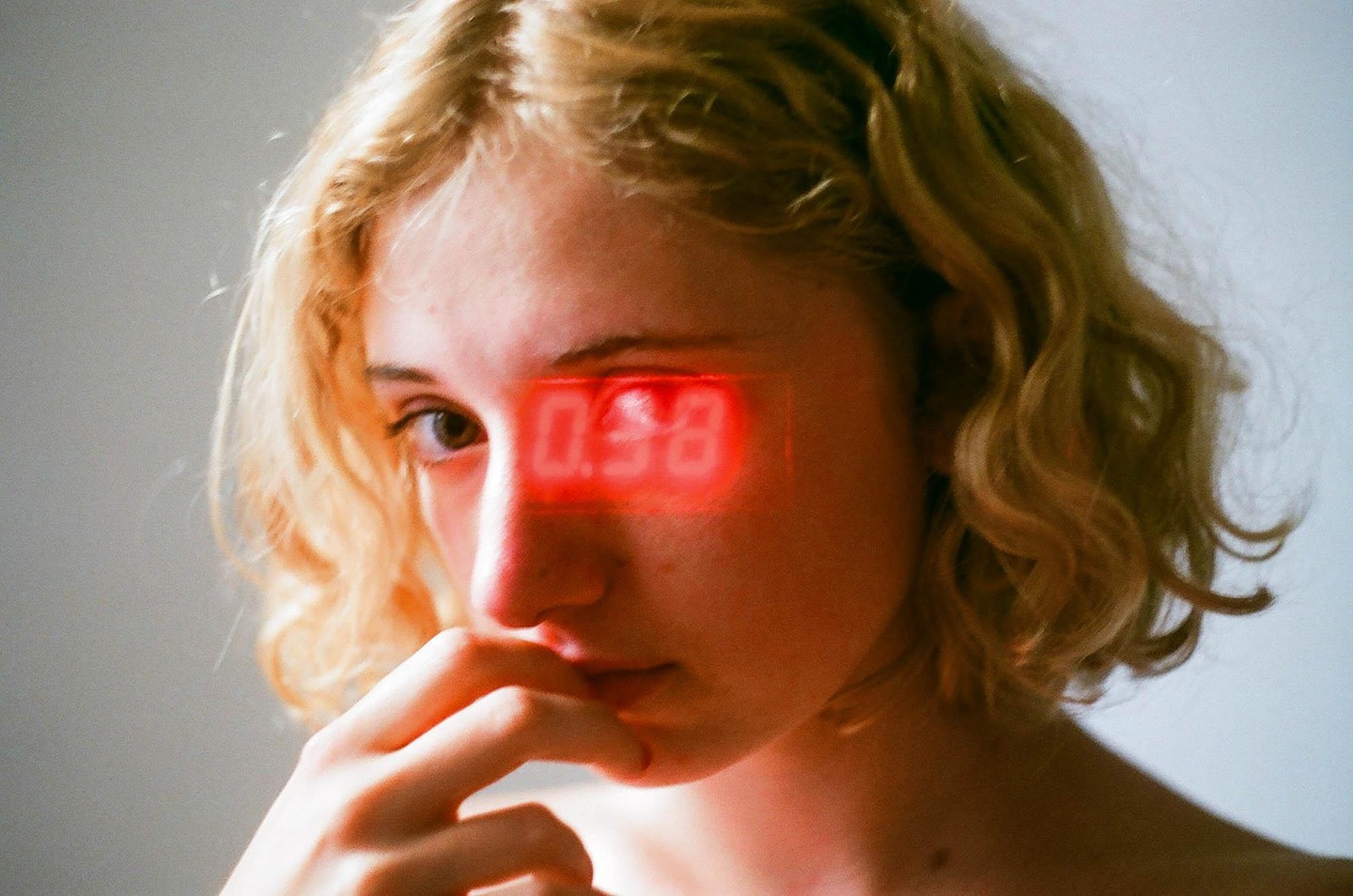 A woman with curly hair has a red digital display over her eye.