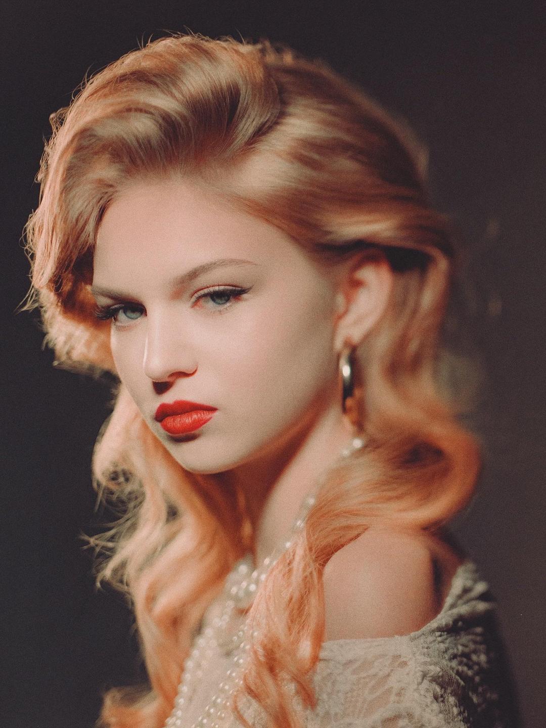 A woman with red lipstick and an earring looks toward the viewer.