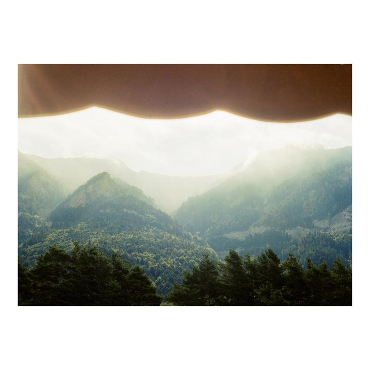 A hazy mountain landscape with a dark, wavy shape at the top of the frame.