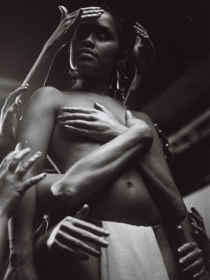 A woman is surrounded by many hands touching her body and head.