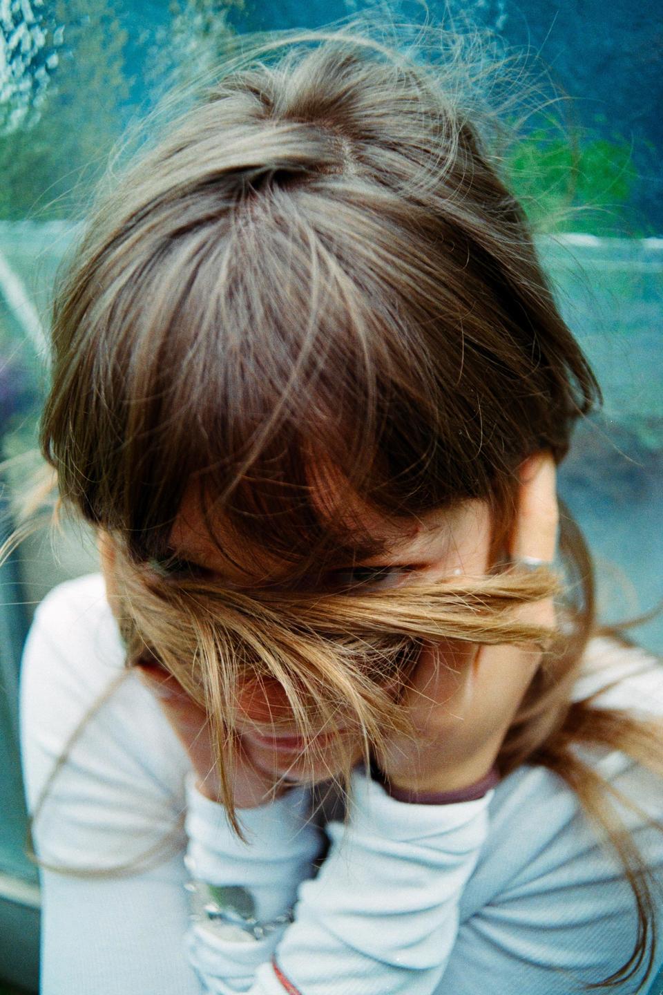 A girl with her face partially obscured by her hair is looking down.