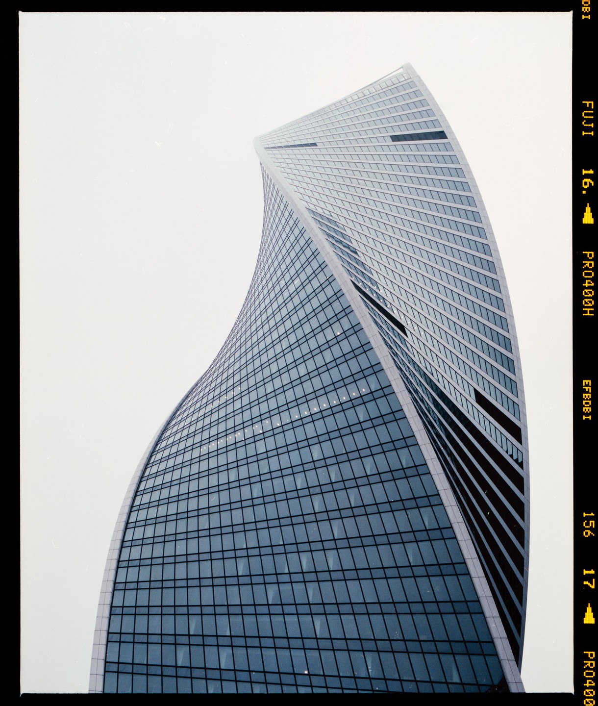 A modern skyscraper with a twisting design and glass facade rises against a bright sky.