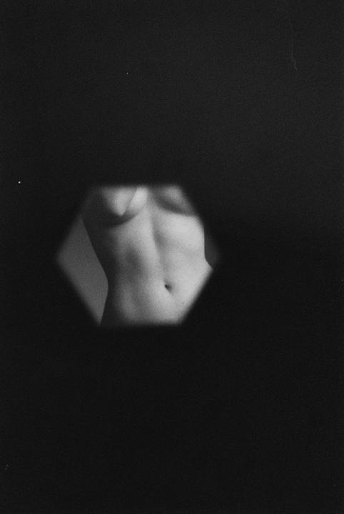 A woman's torso is visible through a hexagonal opening in a black background.