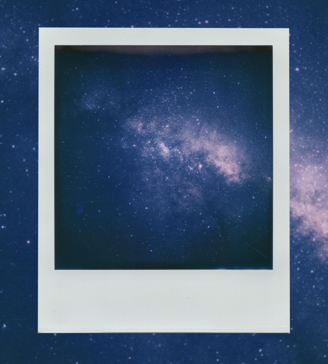 A polaroid photograph of the milky way core is placed on a background of the milky way.