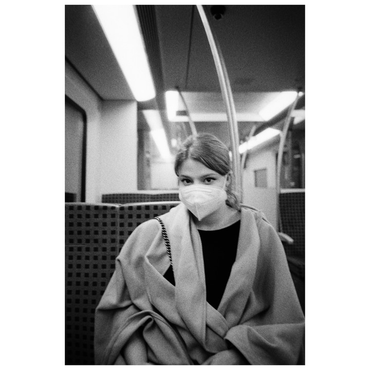 A woman wearing a face mask sits on a train.