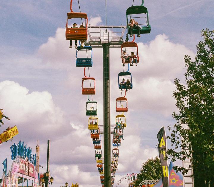 People ride in colorful gondolas on a sky ride attraction at a fairground.