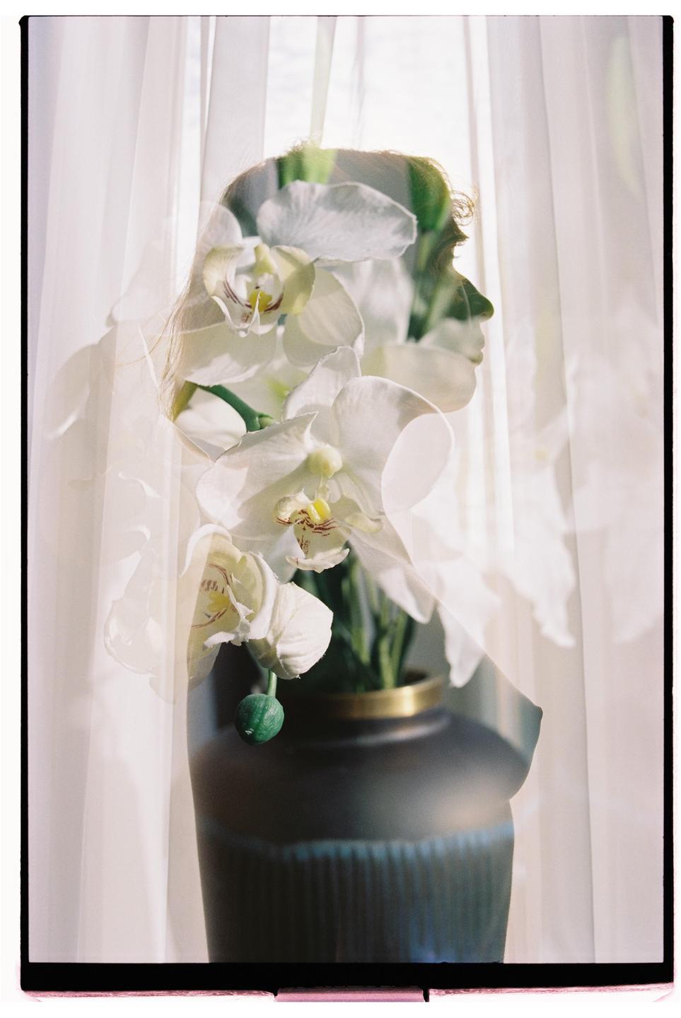 A double exposure shows a woman's profile overlaid with white orchids in a vase.