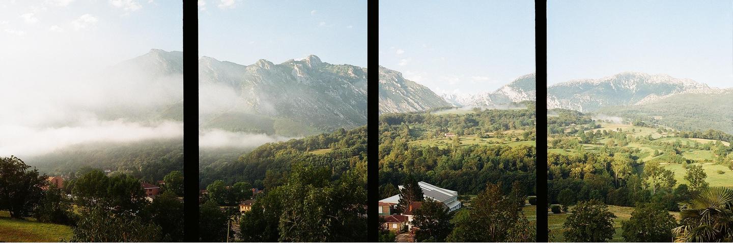 A panoramic view shows a valley with mountains, trees, and some buildings, with fog covering parts of the landscape.