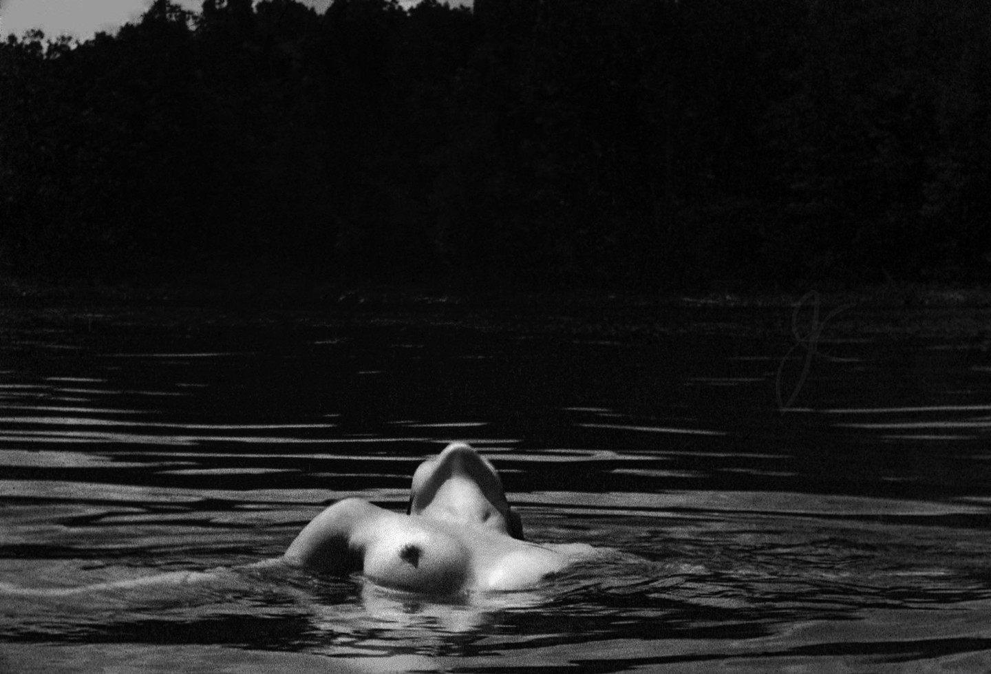 A woman floats on her back in water with her head tilted back and her chest exposed.