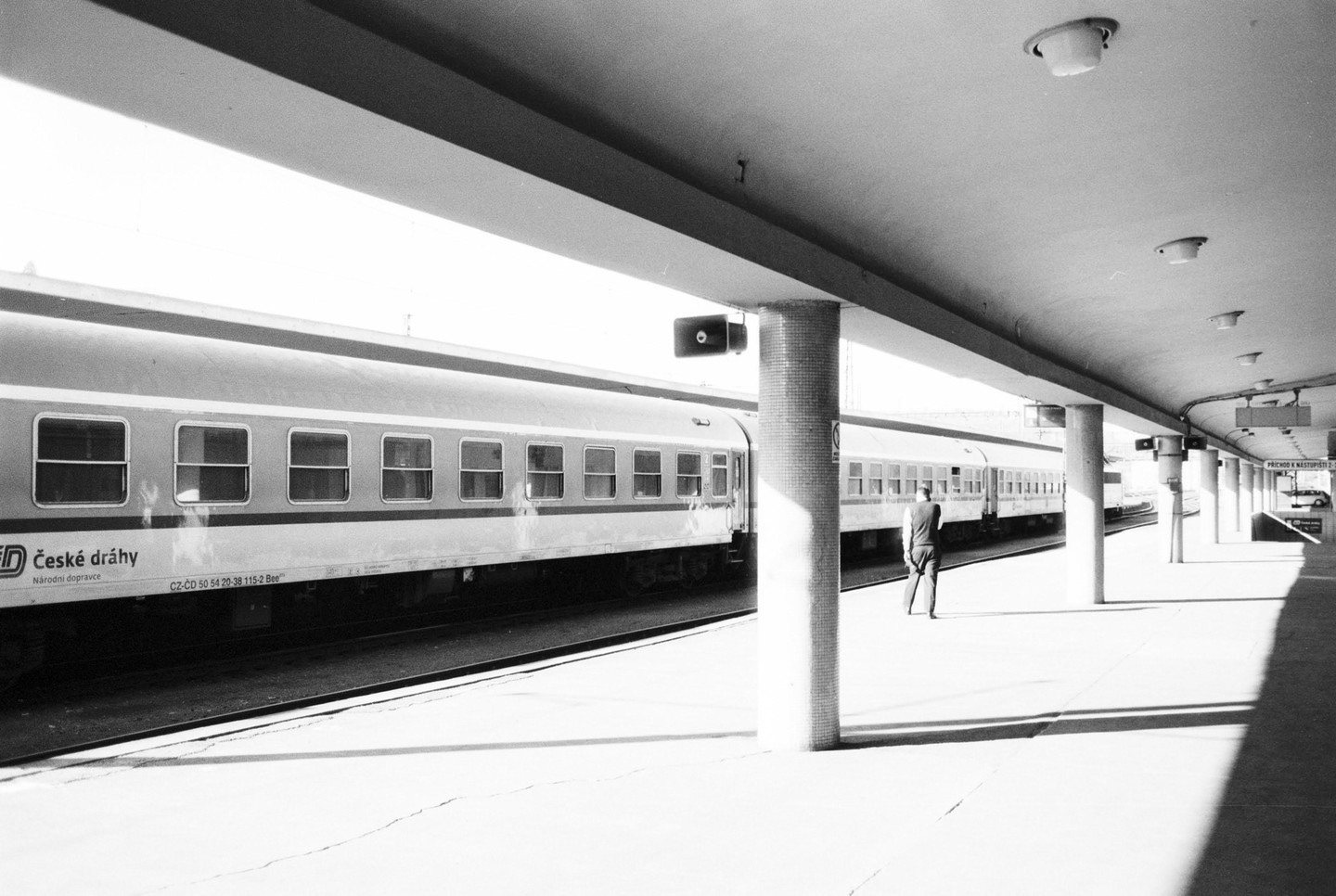 A man stands on a train platform next to a train.