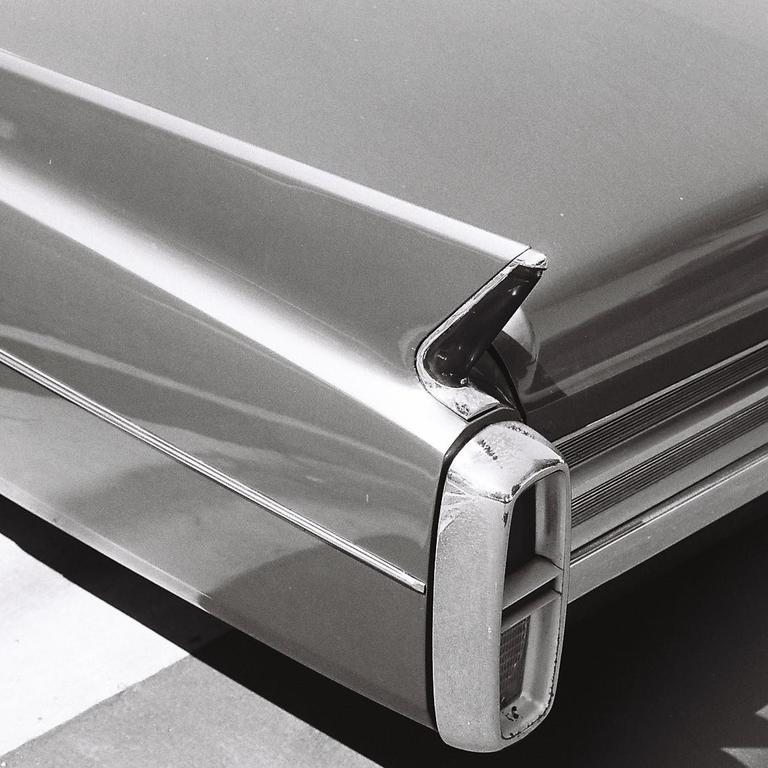 The rear of a vintage car with a prominent taillight is shown in monochrome.