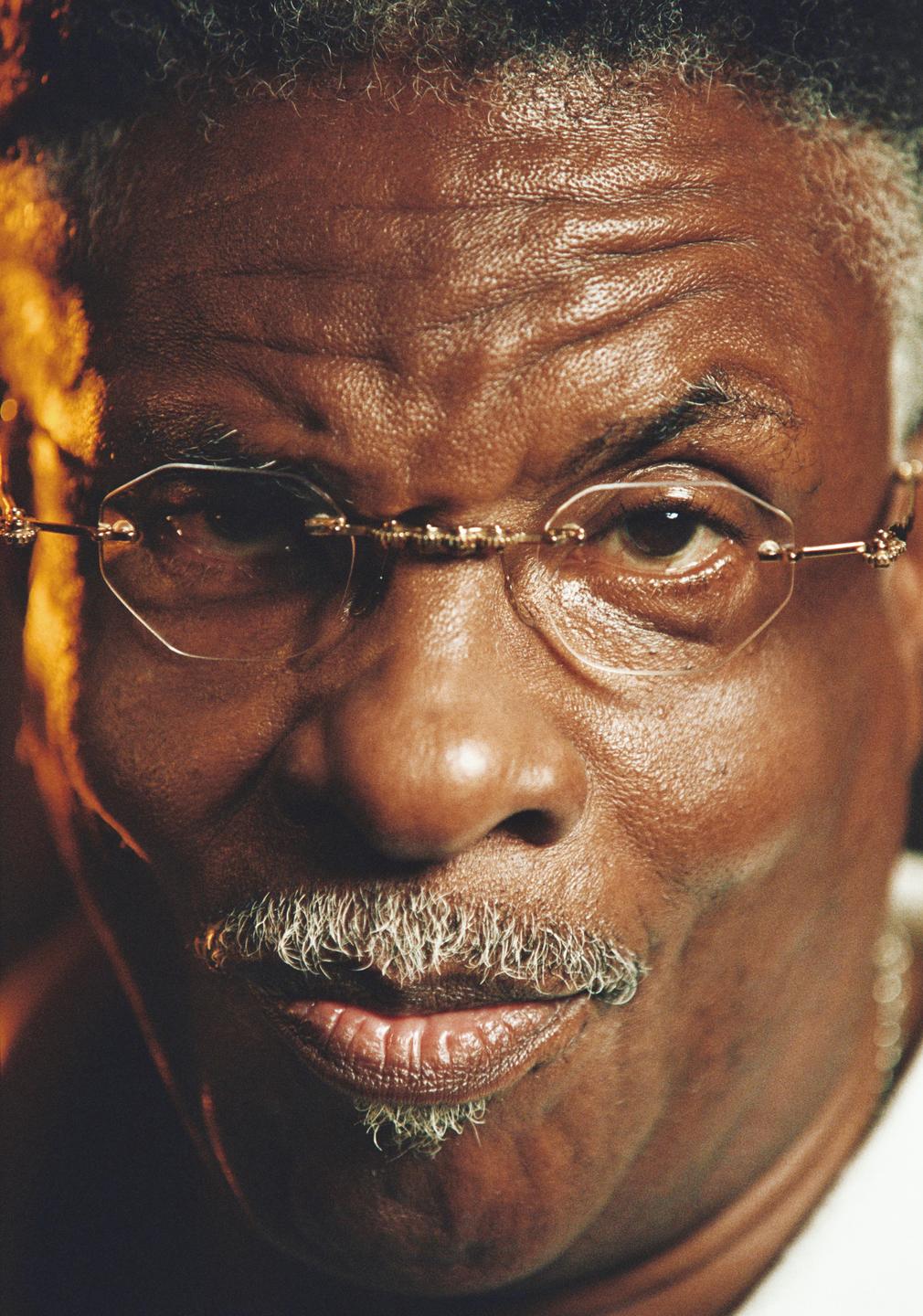 A man with a mustache and glasses looks directly at the viewer.
