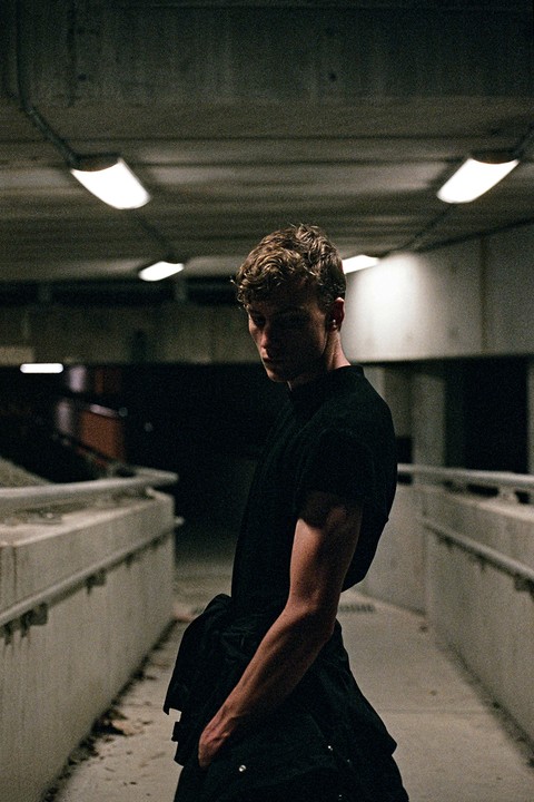A man stands in an underpass with fluorescent lights on the ceiling.