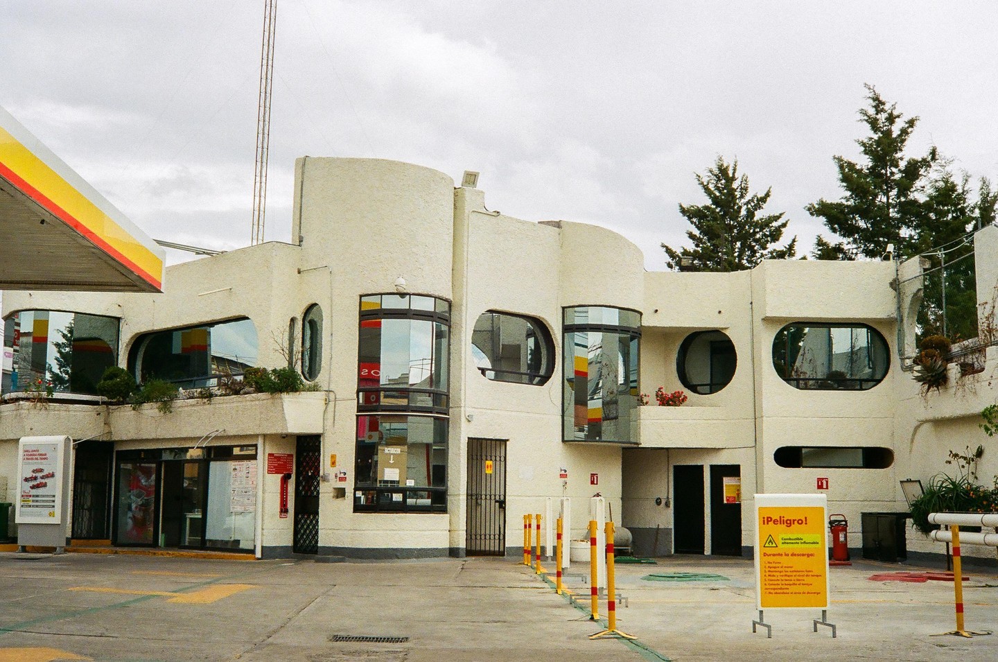 A Shell gas station with a distinctive curved building and various windows is visible under a cloudy sky.