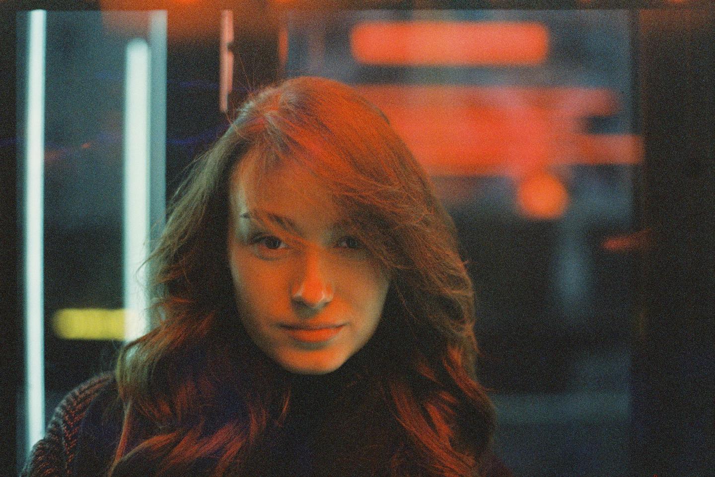 A woman with long hair is illuminated by red and blue neon light.