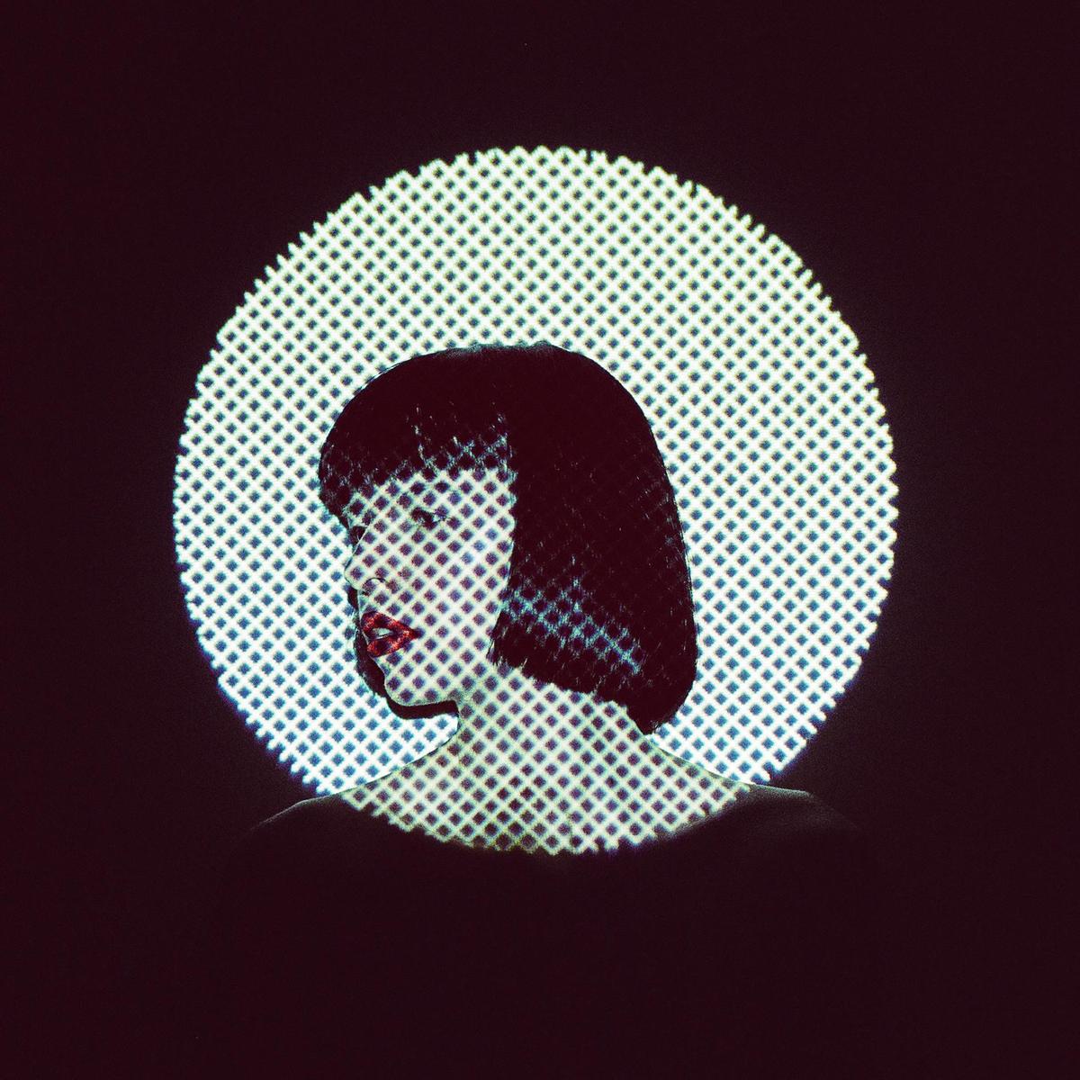 A woman with short dark hair is illuminated by a patterned circular light.