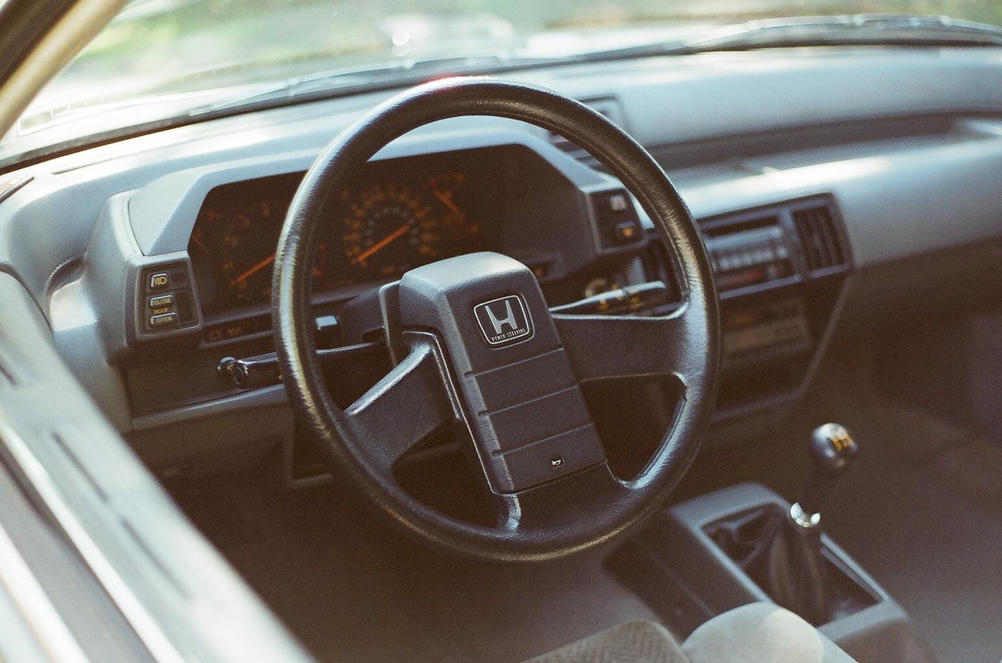 The interior of a car shows the steering wheel, dashboard, and gear shift.