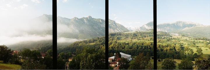 A panoramic view shows a valley with mountains, trees, and some buildings, with fog covering parts of the landscape.