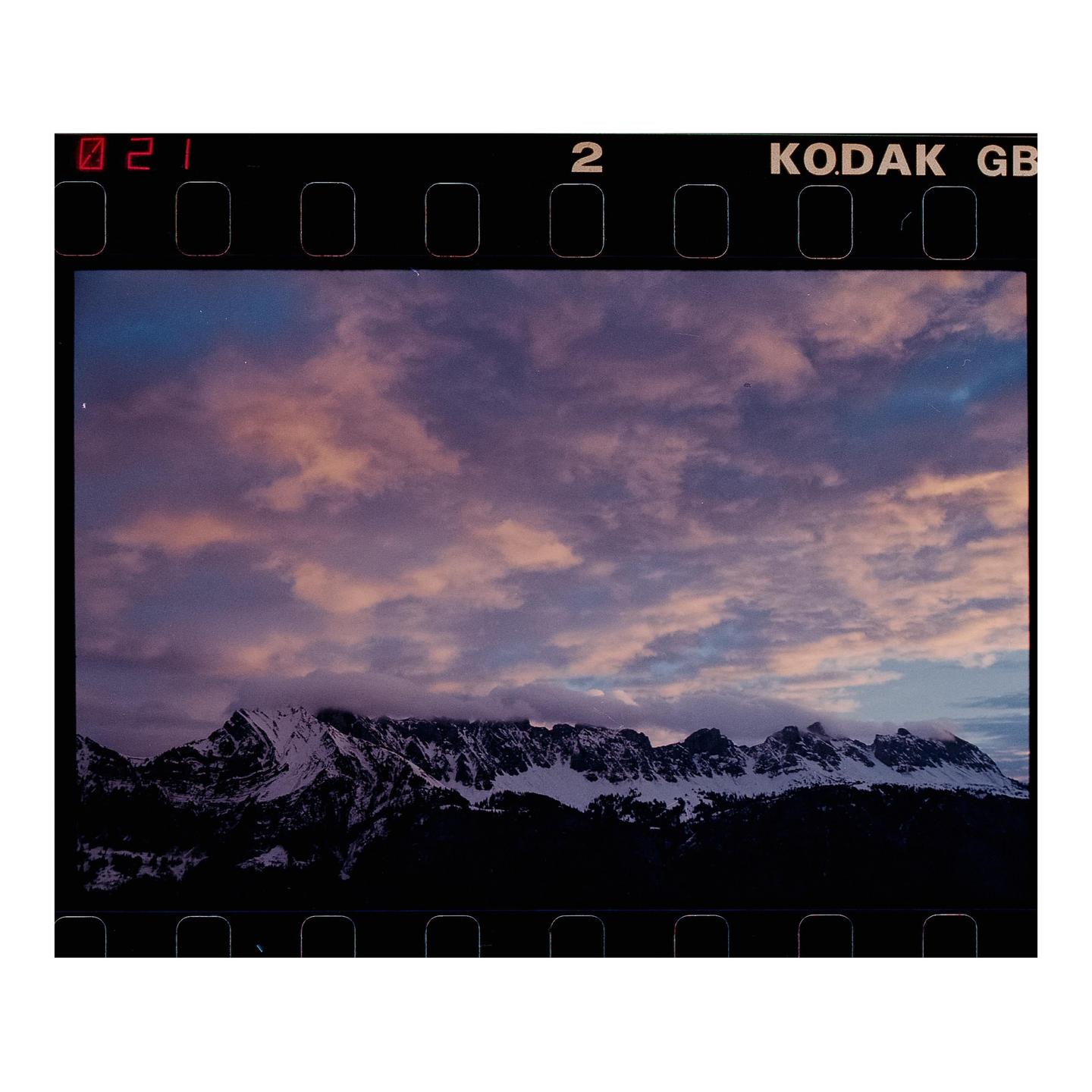 Snow-capped mountains are visible under a cloudy sky at dusk.