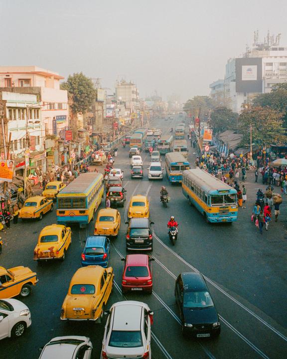 A busy street is filled with cars, buses, and people walking on the sidewalks.