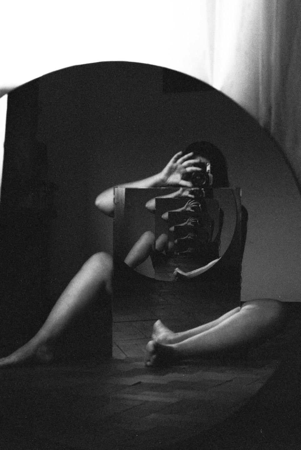 A woman takes a self-portrait in a mirror, which reflects another mirror, creating an infinite reflection.