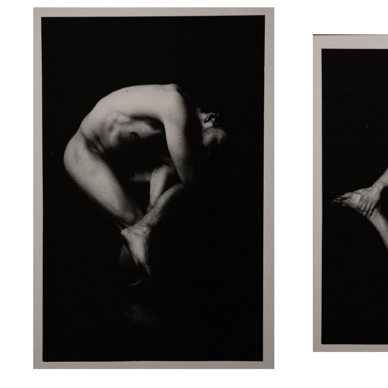 A nude man is curled up on a dark background with his head tilted back.