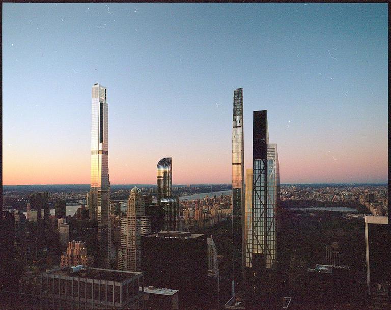 A cityscape with several tall skyscrapers reflecting the light of the setting sun.