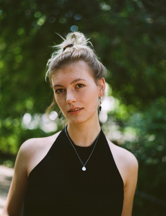 A woman with freckles and a bun looks at the viewer.