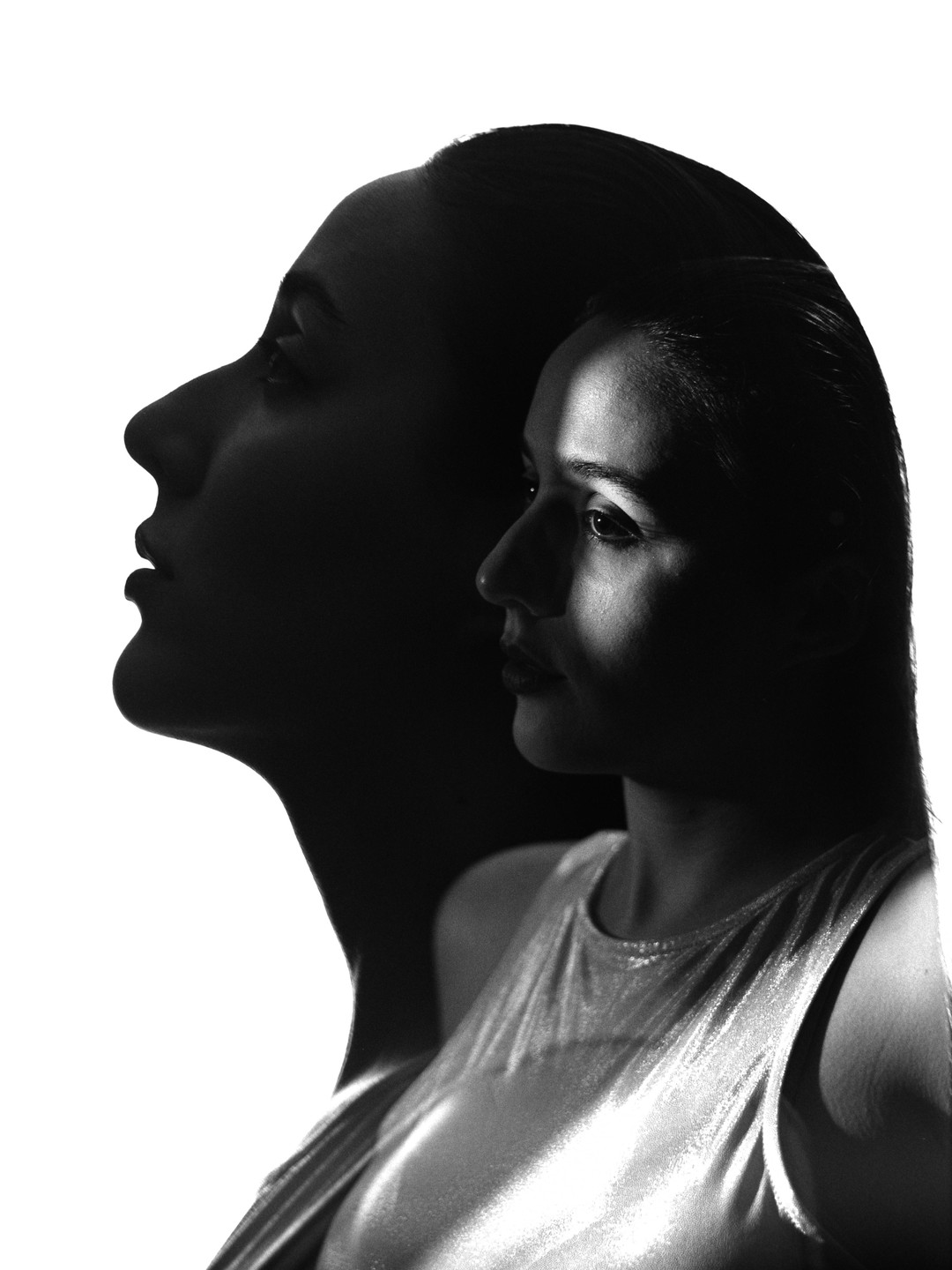 A double exposure shows a woman's profile in shadow and her face partially lit by a beam of light.