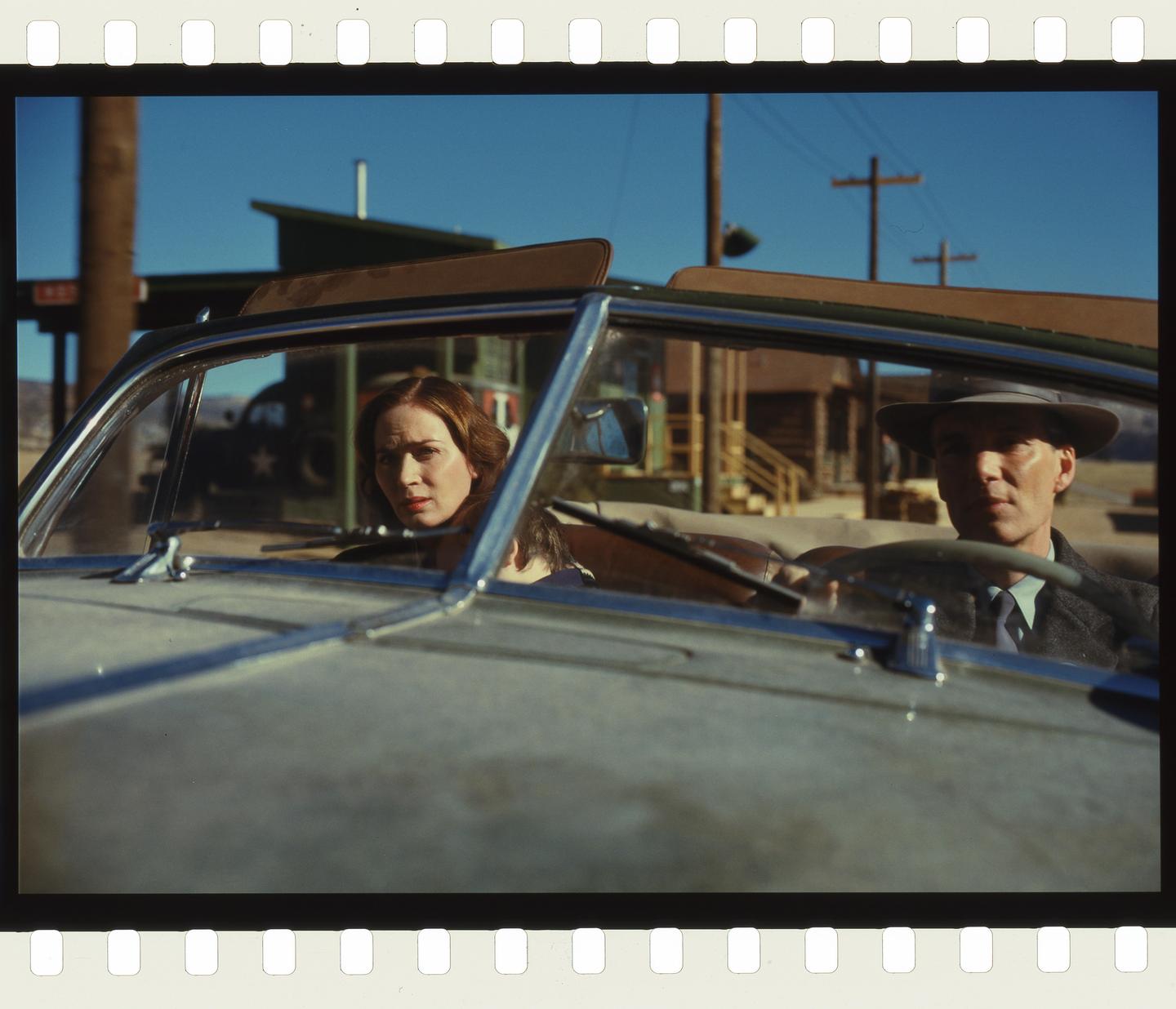 A man in a hat and a woman are sitting in a convertible car.