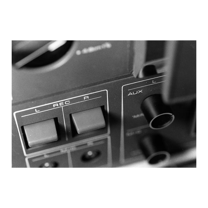 A close-up, black and white shot shows the buttons and dials of an audio recording device.