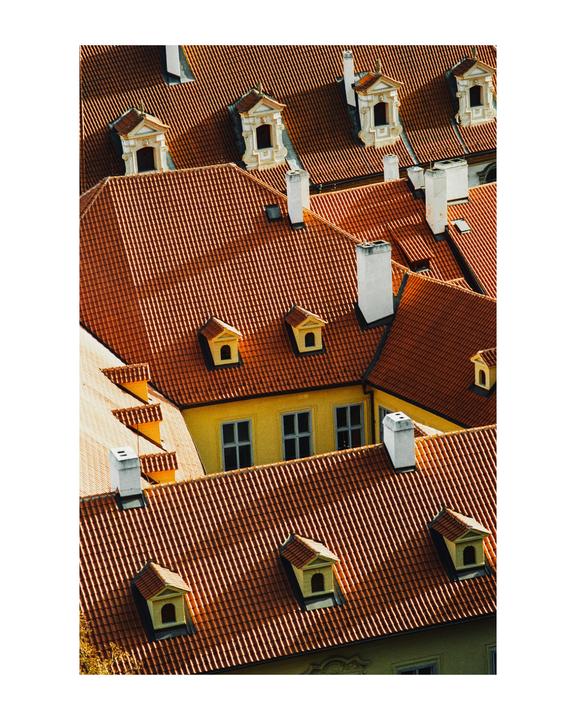 An aerial view shows many red tile rooftops with dormer windows and chimneys.