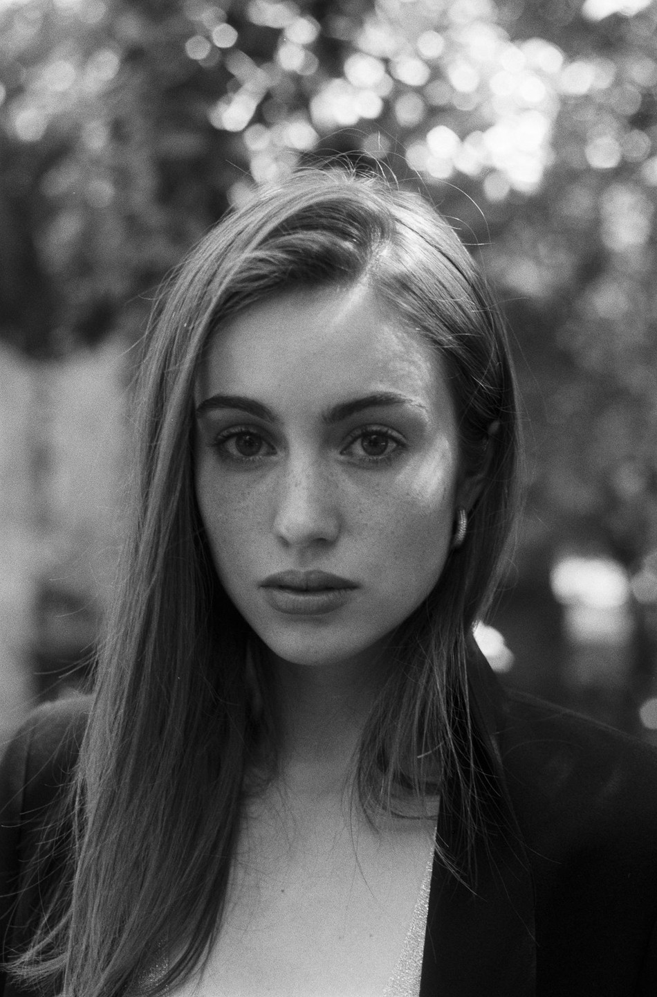 A woman with long hair and freckles looks directly at the camera in a close-up portrait.