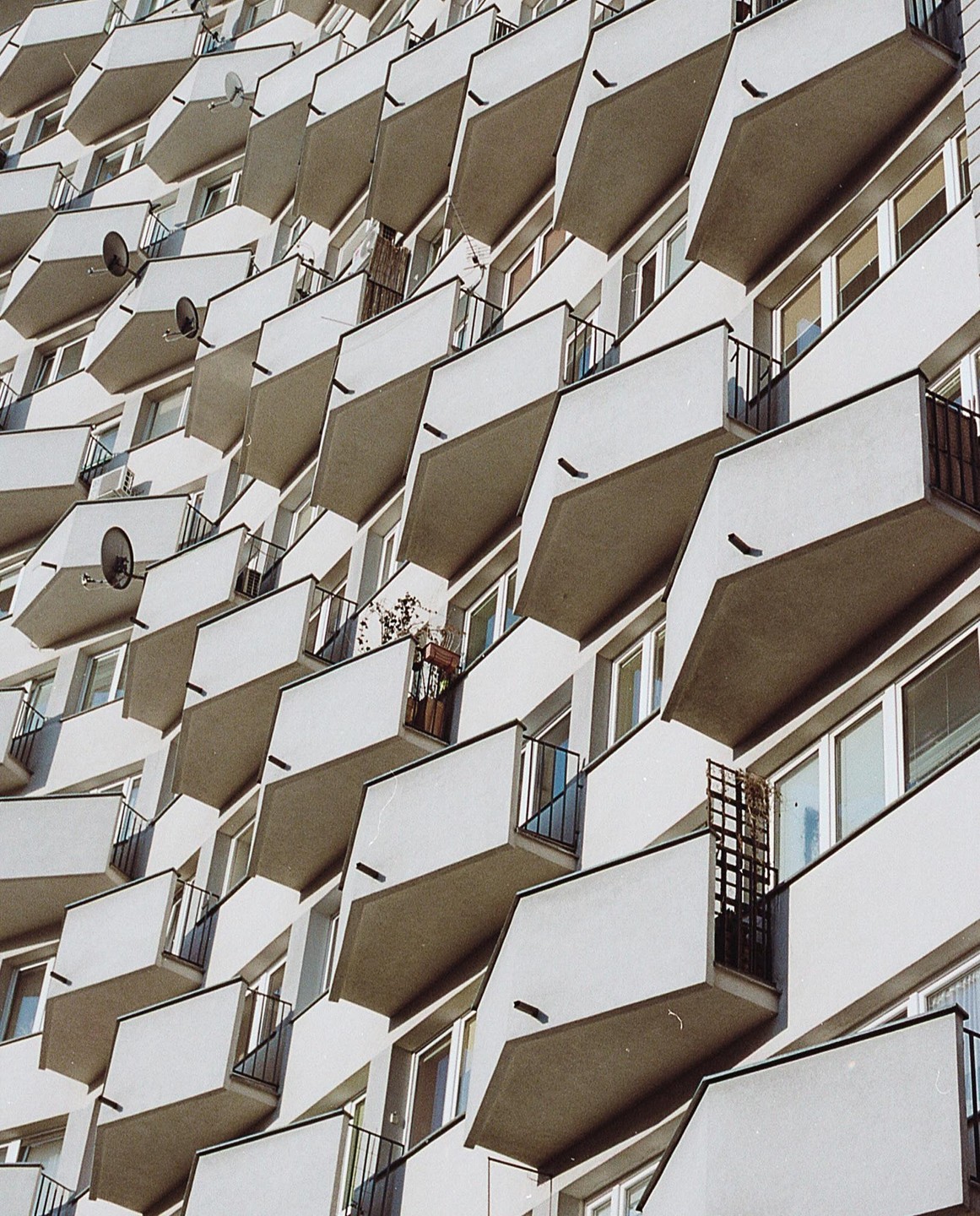 A building with many balconies and satellite dishes is shown from a low angle.
