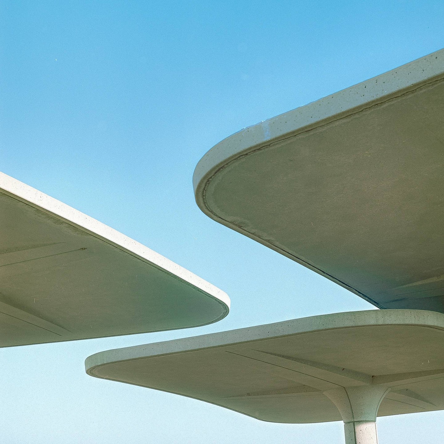 Three concrete structures with rounded edges are visible against a clear blue sky.