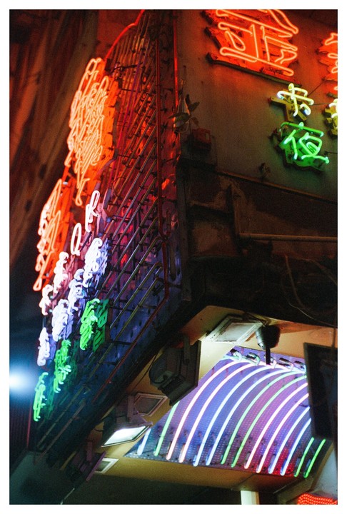 A building facade is covered in colorful neon signs with Chinese characters.