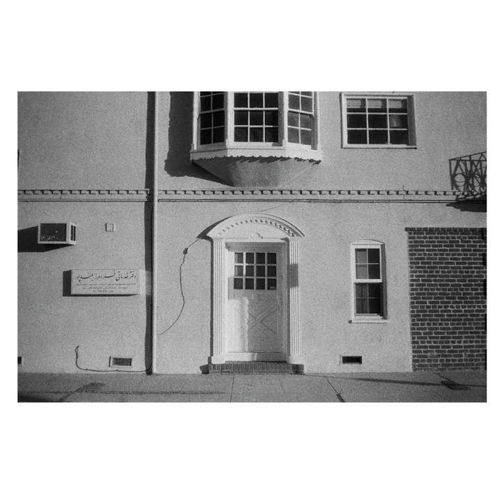A building with a bay window, a door, and a sign with text in a non-Latin script is shown.