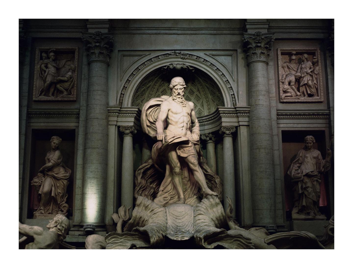A large stone statue of a man stands in a niche, surrounded by other statues and architectural details.